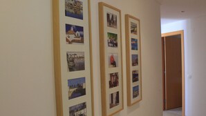 A hallway with framed photographs on the wall, a wooden door, and a tiled floor. - Cabanas Gardens,  4px, pool view (Cabanas de tavira)