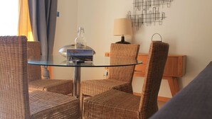 A glass-top table with wicker chairs, a lamp, and a bottle on it. - Cabanas Gardens,  4px, pool view (Cabanas de tavira)