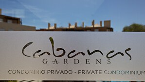 A sign for 'Cabanas Gardens Condominium' with a clear view of the building in the background. - Cabanas Gardens, 4px, pool viewr (Cabanas de tavira)