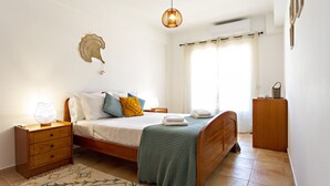 Un dormitorio con cama, mesita de noche, lámpara y un adorno en la pared.