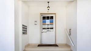 Una puerta blanca con un panel de vidrio y una lámpara sobre la puerta. Encima, un pequeño letrero.