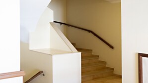 Una escalera con barandilla de madera y paredes color beige.