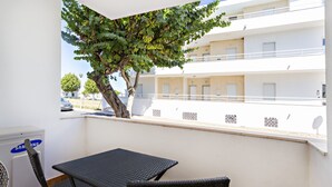 A balcony with a table and chairs, a Samsung air conditioner, and a tree.