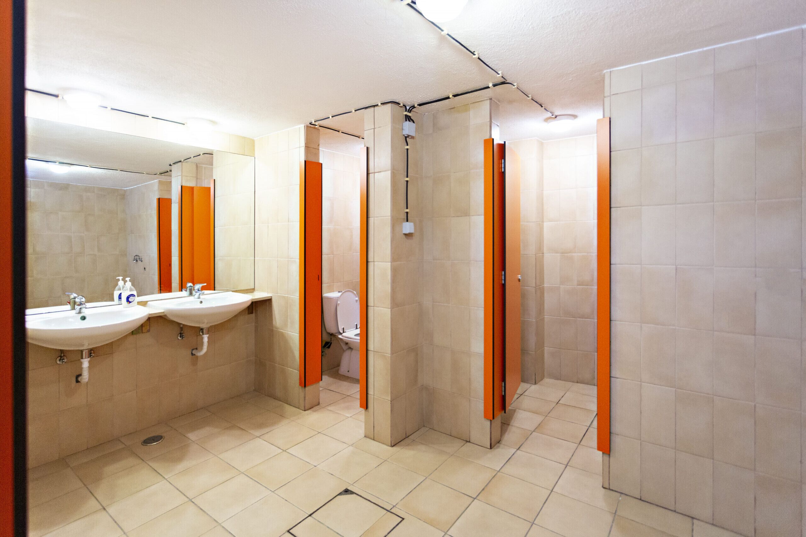 A public restroom with two sinks, a toilet, and a shower area.