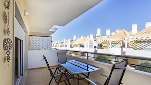Un balcón con mesa y sillas, un muro con diseño y vistas a edificios.