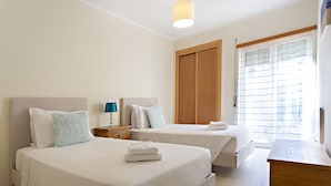 Una habitación de hotel con dos camas, un armario de madera, un escritorio y una ventana con persianas.