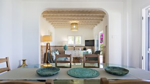 A dining area with a glass table, wooden chairs, and a kitchen in the background. - Beach house, 2 steps from the ocean! (Faro)