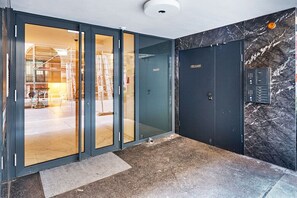 A modern entrance with a glass door, a marble wall, and a security keypad.