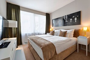 A hotel room with a large bed, a desk, a TV, and a painting on the wall.