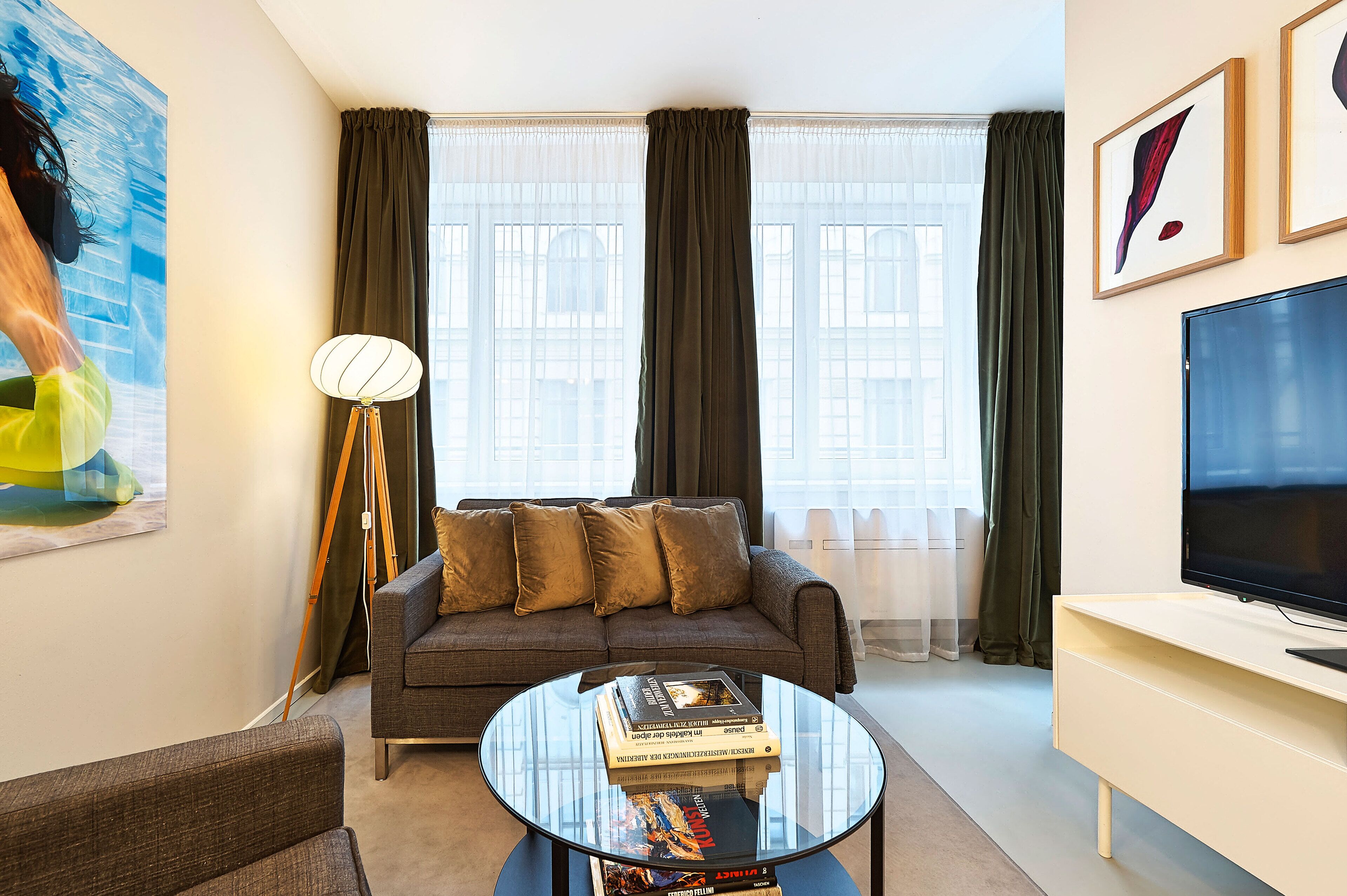 Een moderne woonkamer met een bank, een ronde glazen salontafel en een flatscreen televisie.