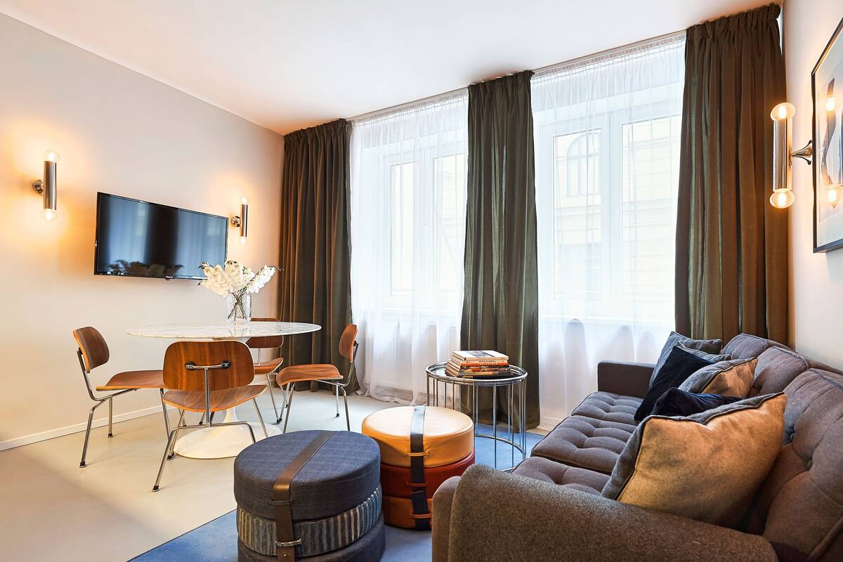 A modern living room with a sofa, ottoman, and dining table.
