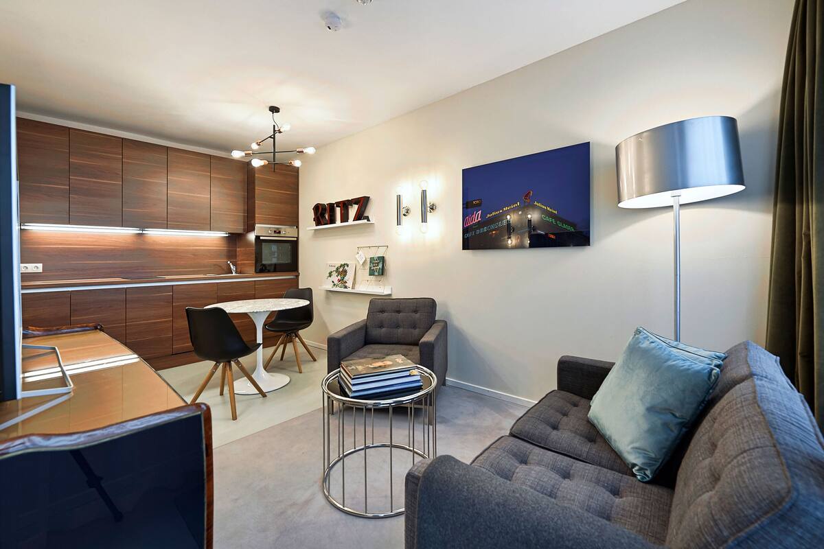 A modern living room with a grey sofa, a small round coffee table, and a dining area with a white table and chairs.