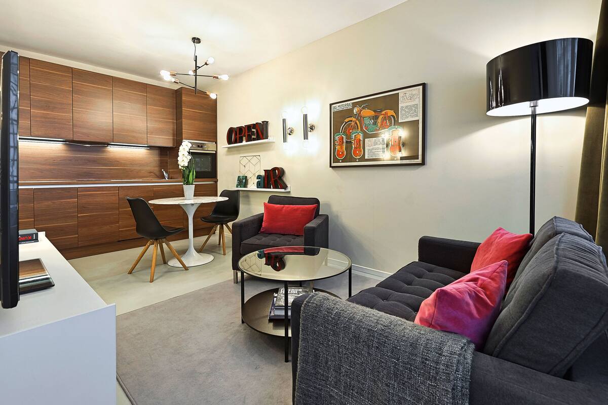 A modern living room with a sofa, coffee table, and a dining area with a table and chairs.