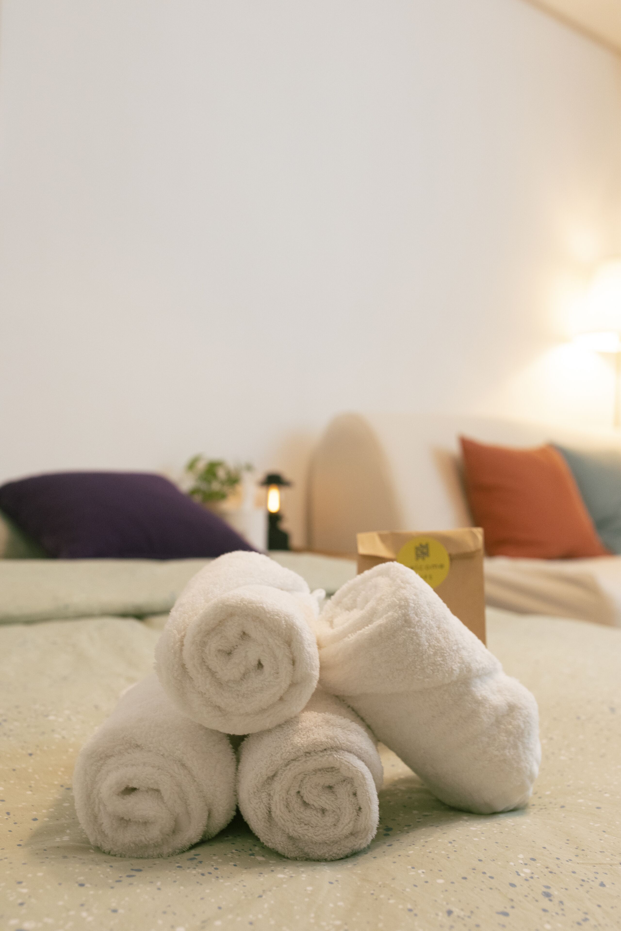 A neatly arranged stack of white towels on a bed with a green bedspread.