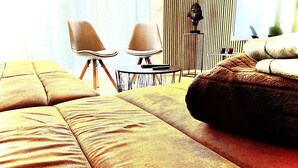 A modern living room with a large sectional sofa, two armchairs, a small round table, and a decorative bust on a stand. - Nivas - 2 rooms, kitchen, bathroom, 6 persons (Montabaur)