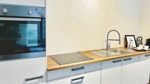A modern kitchen with a built-in oven, a stainless steel sink, and wooden countertops. - Nivas - 2 rooms, kitchen, bathroom, 6 persons (Montabaur)