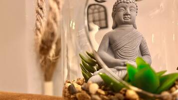 Una statua di Buddha all'interno di un contenitore di vetro trasparente, con ciottoli e piante verdi.