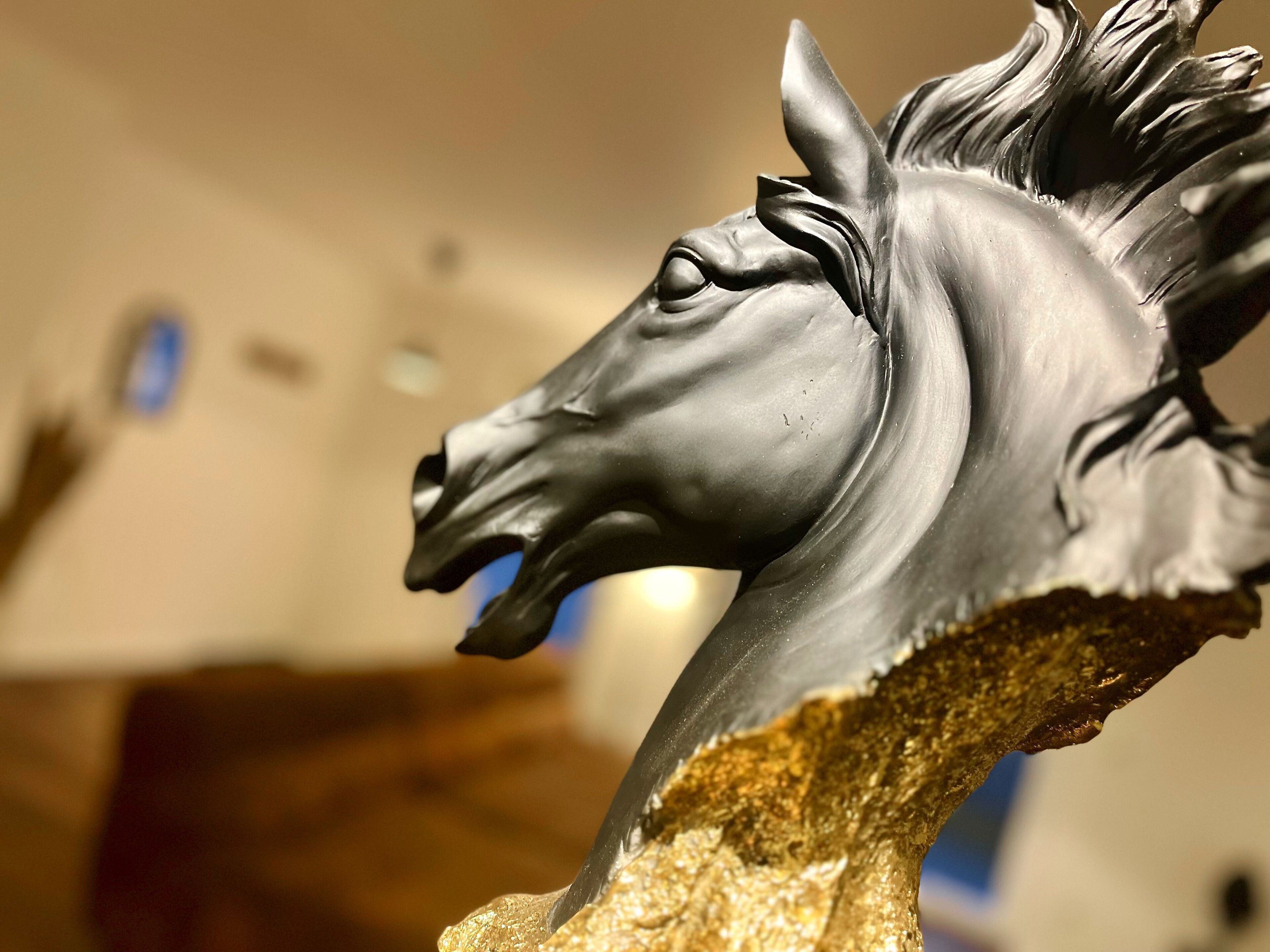 Primer plano de una escultura con cabeza de caballo sobre un pedestal texturizado.