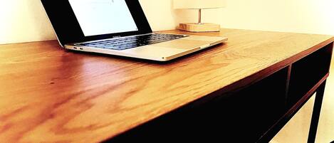 A laptop on a wooden desk with a lamp beside it.