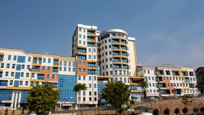 A multi-story hotel with a modern design, featuring a prominent curved structure and multiple balconies. - Tropical Plaza Apartments (Kigali)
