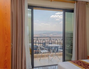 A room with a balcony, a bed, and a view of the cityscape. - Tropical Plaza Apartments (Kigali)