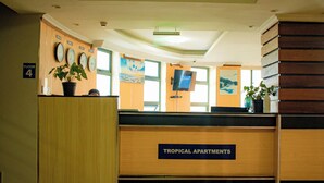 A reception desk with a sign for 'Tropical Apartments' and a floor number sign for 'Floor 4'. - Tropical Plaza Apartments (Kigali)