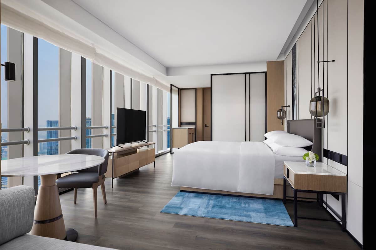 Une chambre d’hôtel moderne dotée d’un grand lit, d’un bureau, d’une chaise, d’une télévision et offrant une vue sur la ville.