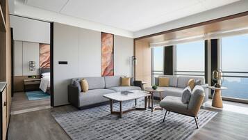 A modern living room with a gray sofa, a coffee table, and a view of the city through large windows.
