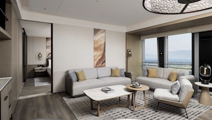 A modern living room with a grey sofa, a coffee table, and a view of the city. - Changzhou Marriott Hotel Jintan (Changzhou)