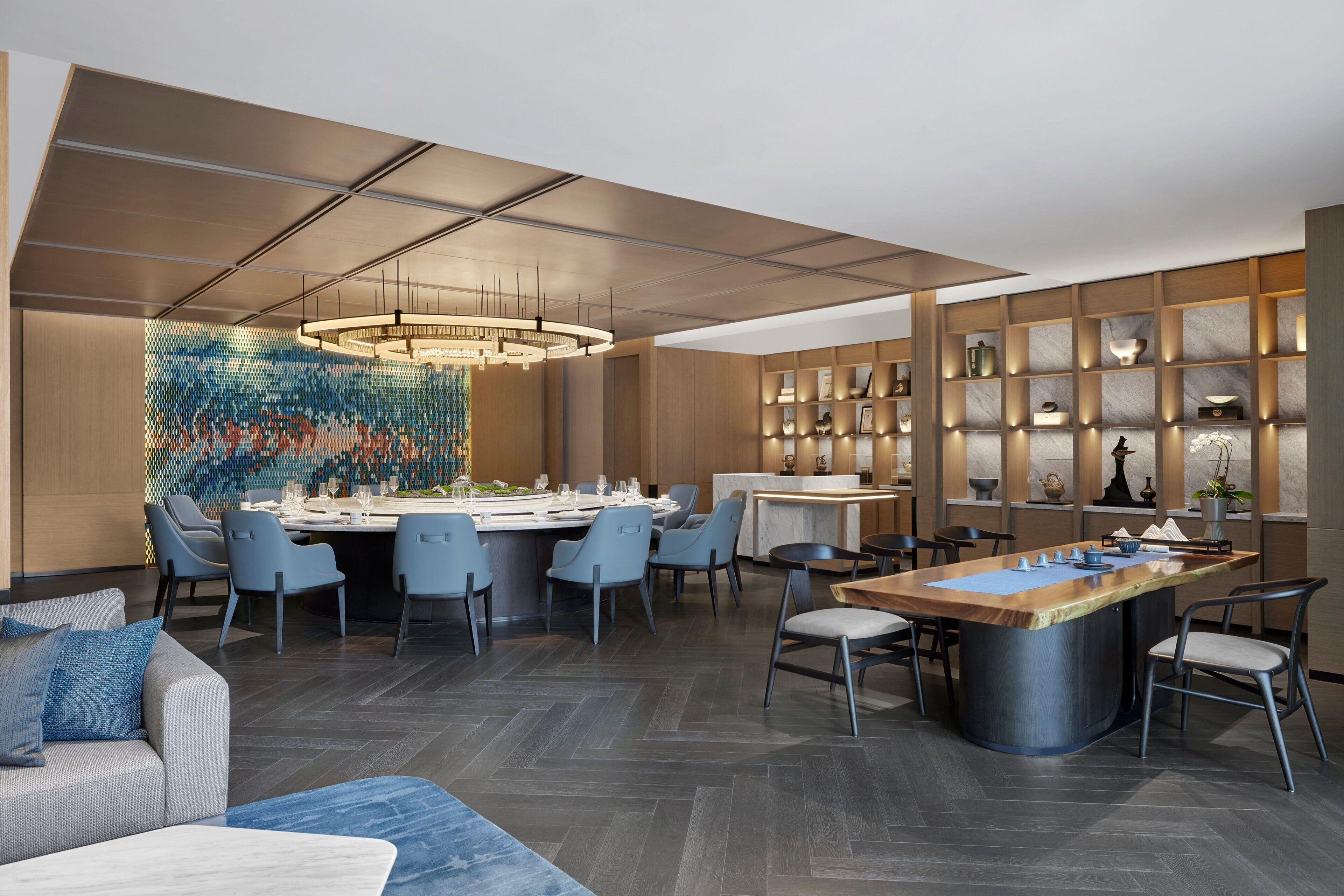 Una cocina moderna con una isla central, comedor con sillas y una pared decorativa.