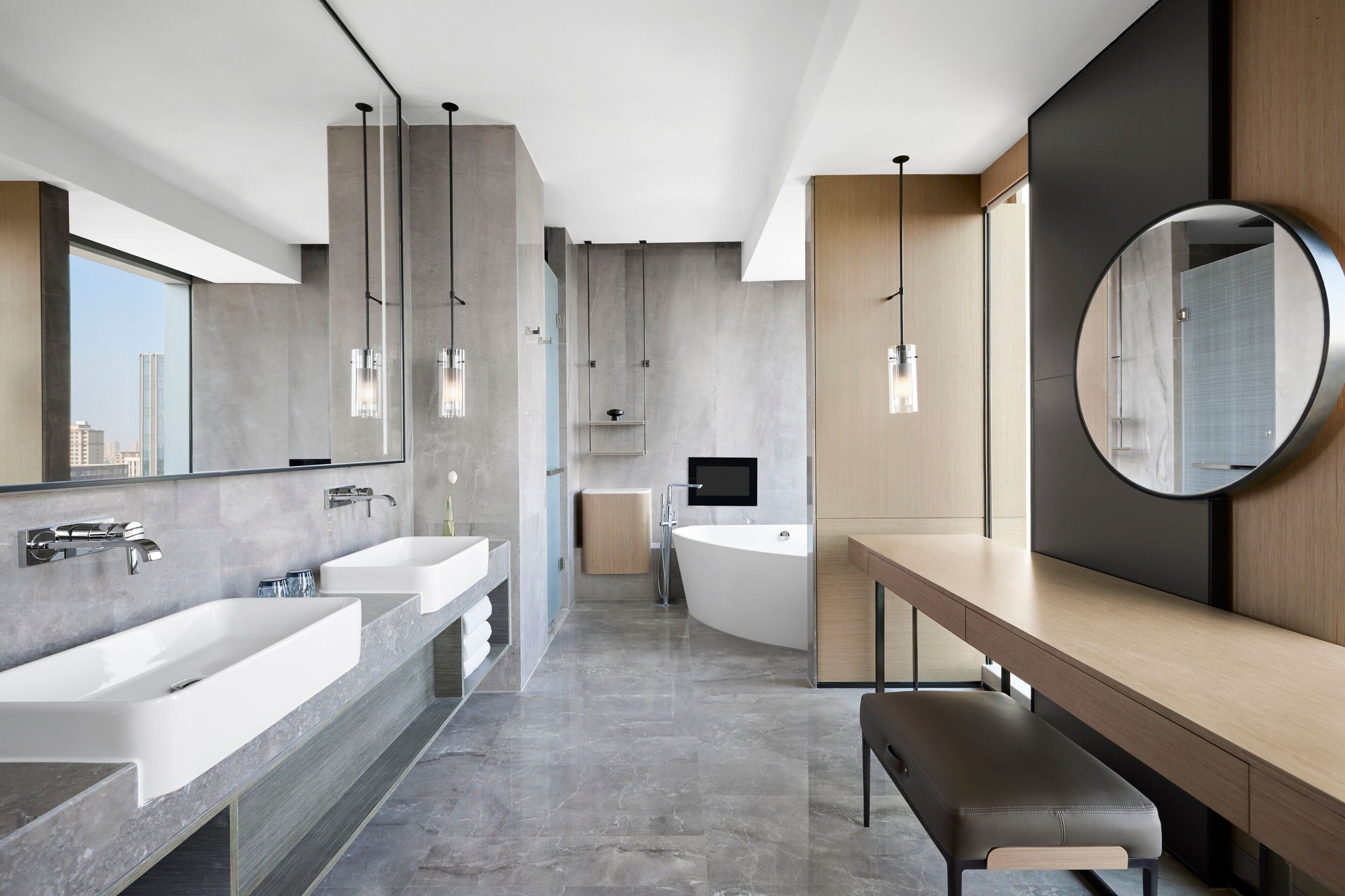 A modern bathroom with two sinks, a bathtub, and a vanity with a mirror.