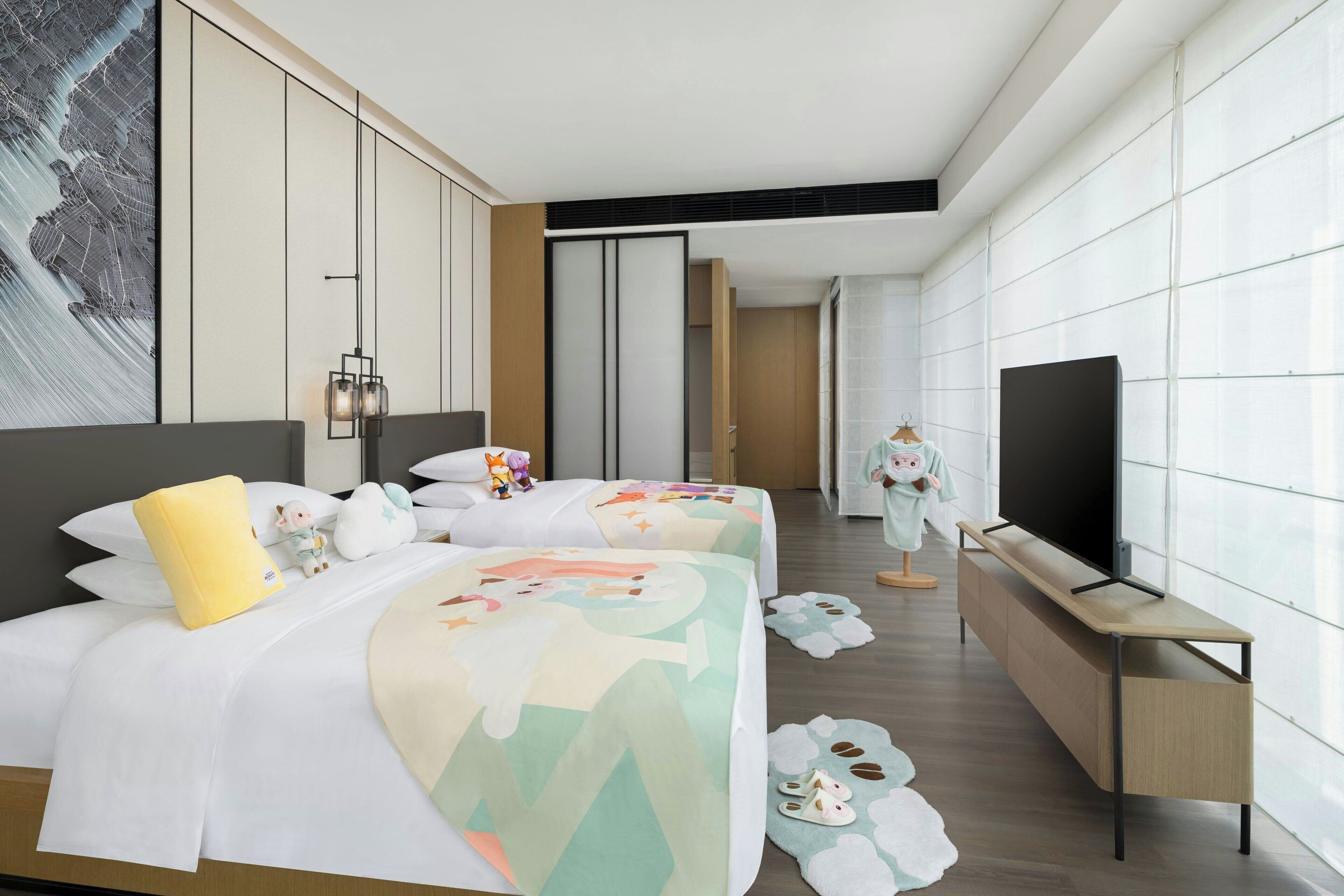 A modern hotel room with a large bed, a TV, and a view of the city.