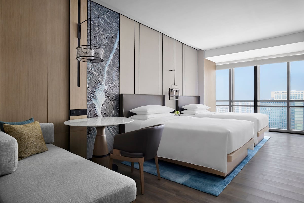 Une chambre d’hôtel moderne dotée d’un grand lit, d’un canapé, d’une table à manger et offrant une vue sur la ville.