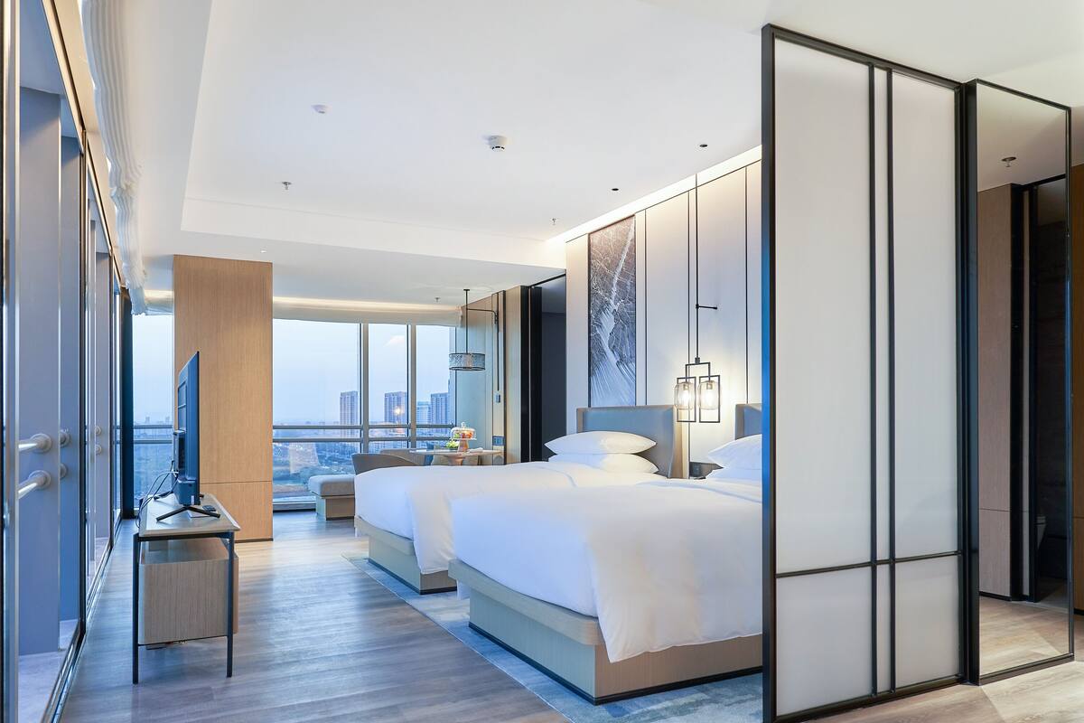 Une chambre d’hôtel moderne avec un grand lit, un bureau et une vue sur la ville.