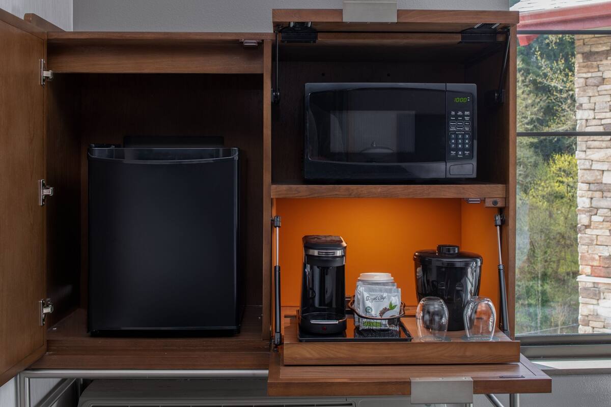 Een keuken met een magnetron, koffiezetapparaat en opbergcontainers.