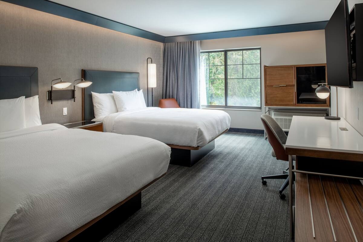 Een hotelkamer met twee bedden, een bureau en een televisie.