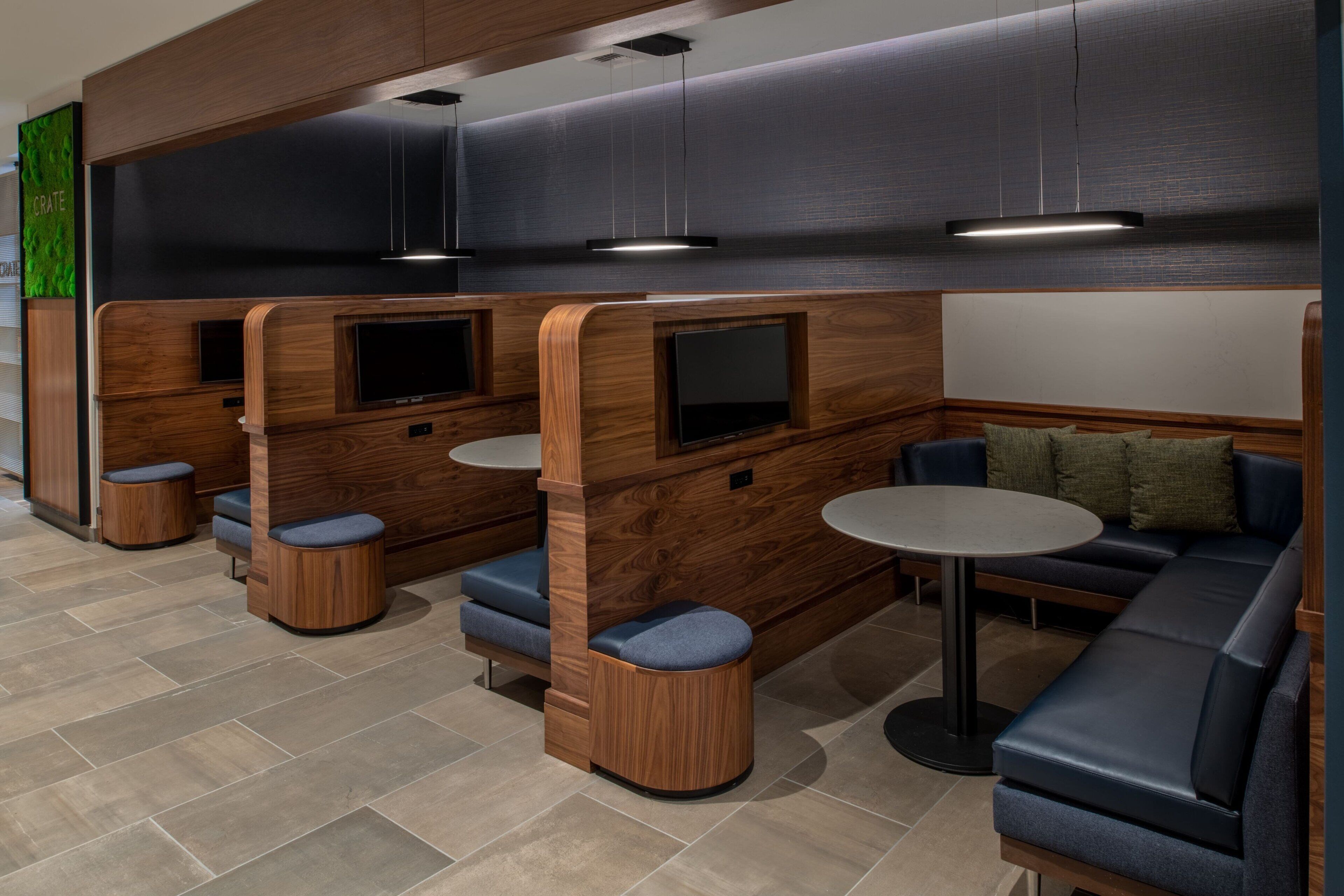 A modern interior with wooden partitions, seating areas, and built-in TVs.