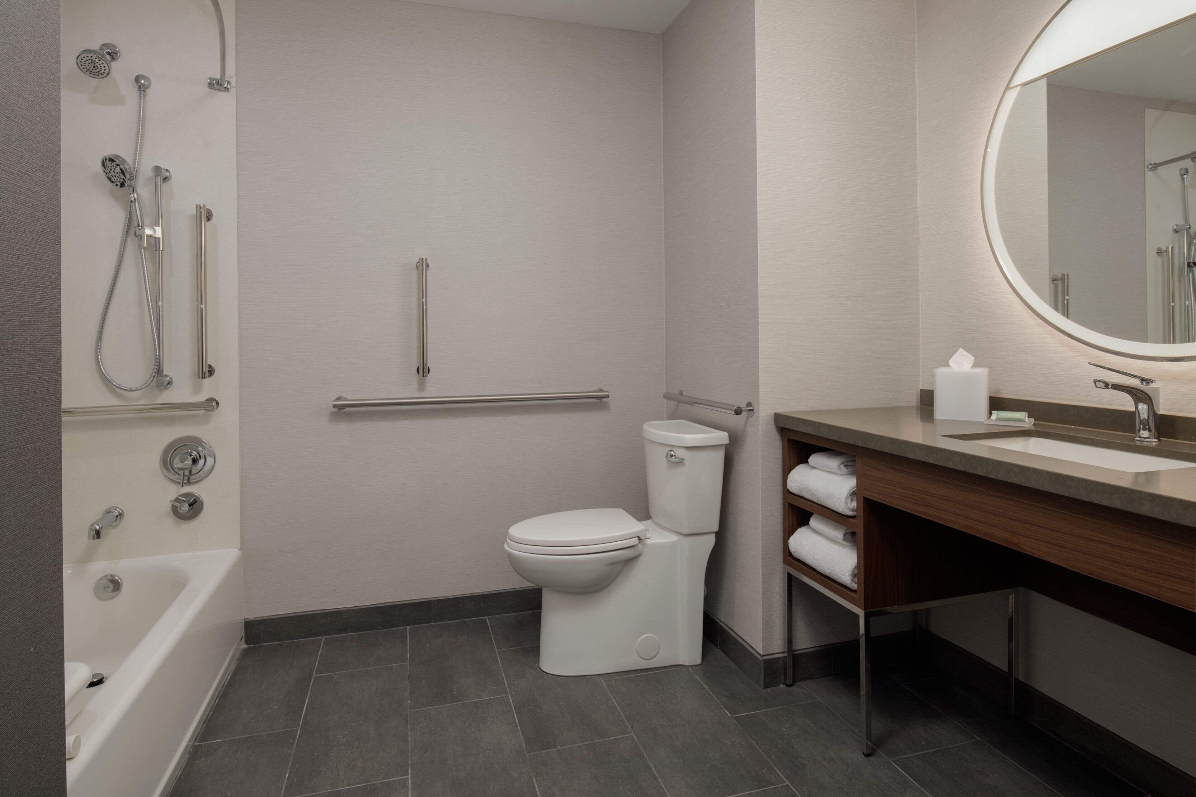 A modern bathroom with a bathtub, toilet, shower, and sink.