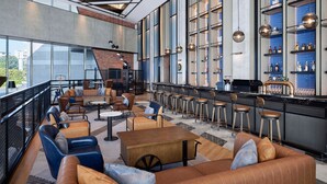 A modern bar area with leather seating, a counter with stools, and a large window overlooking the city. - Four Points By Sheraton Shenzhen Bao'An (Shenzhen)