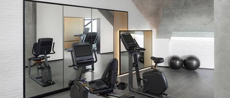 Un gimnasio moderno con equipo de ejercicio, un espejo grande y vistas al cielo.