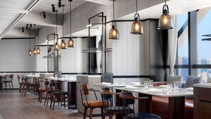 Un restaurant moderne doté de nombreuses tables, de chaises et de luminaires suspendus.