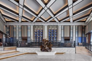 A spacious lobby with a modern design, featuring a central sculpture, a staircase, and a seating area with tables and chairs. - Four Points By Sheraton Shenzhen Bao'An (Shenzhen)