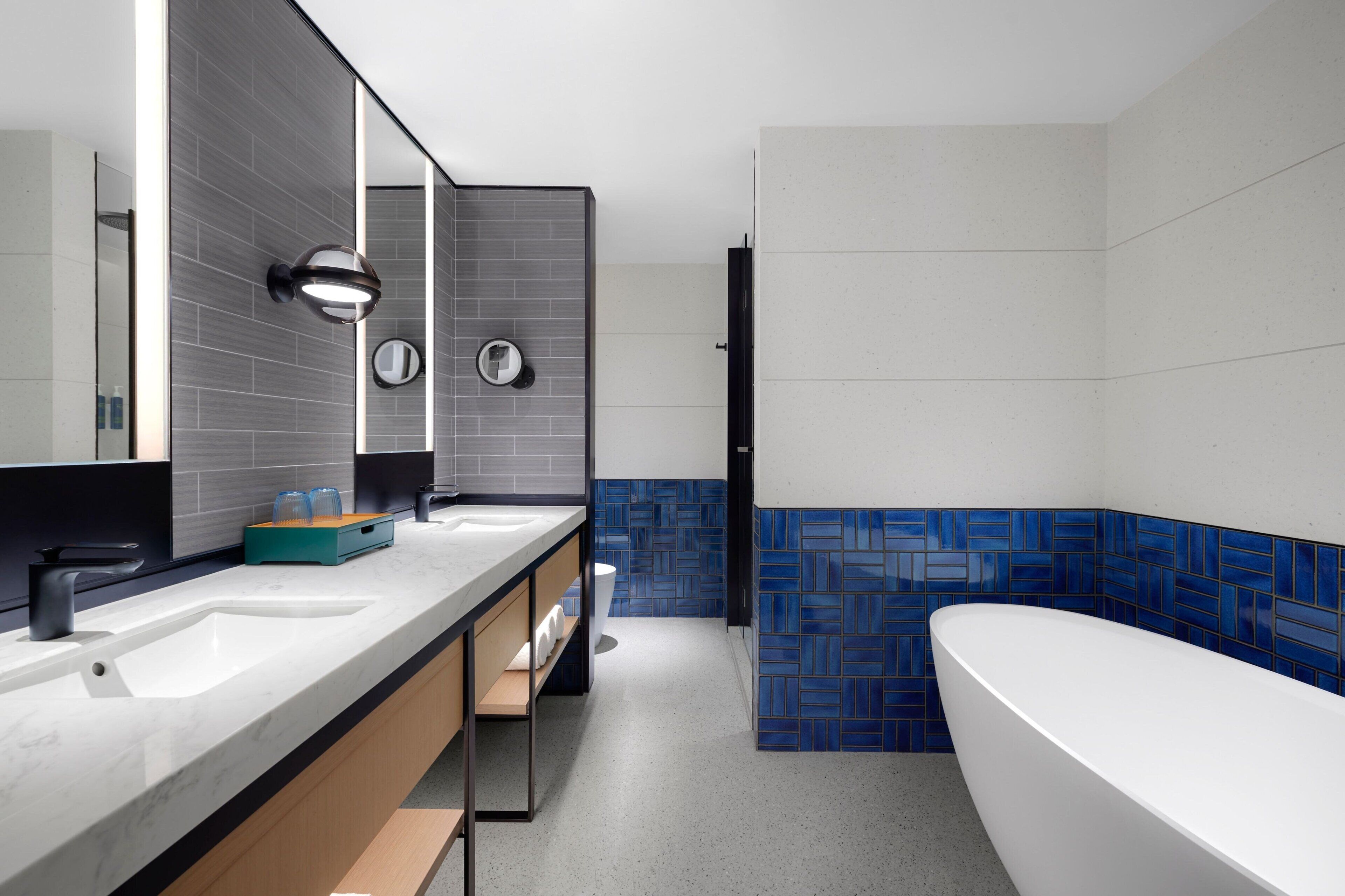 A modern bathroom with a white sink, a mirror, and a bathtub.
