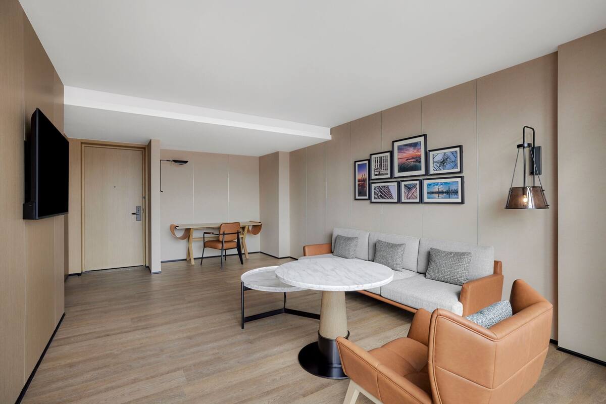 A modern living room with a round table, a sofa, and a TV mounted on the wall.