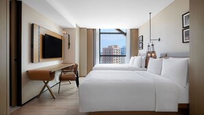 Une chambre d’hôtel avec un grand lit, un bureau avec une chaise, une télévision et une vue sur la ville.