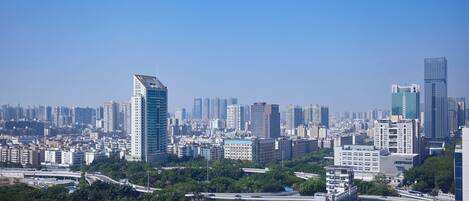 A cityscape with high-rise buildings, a highway, and green areas.