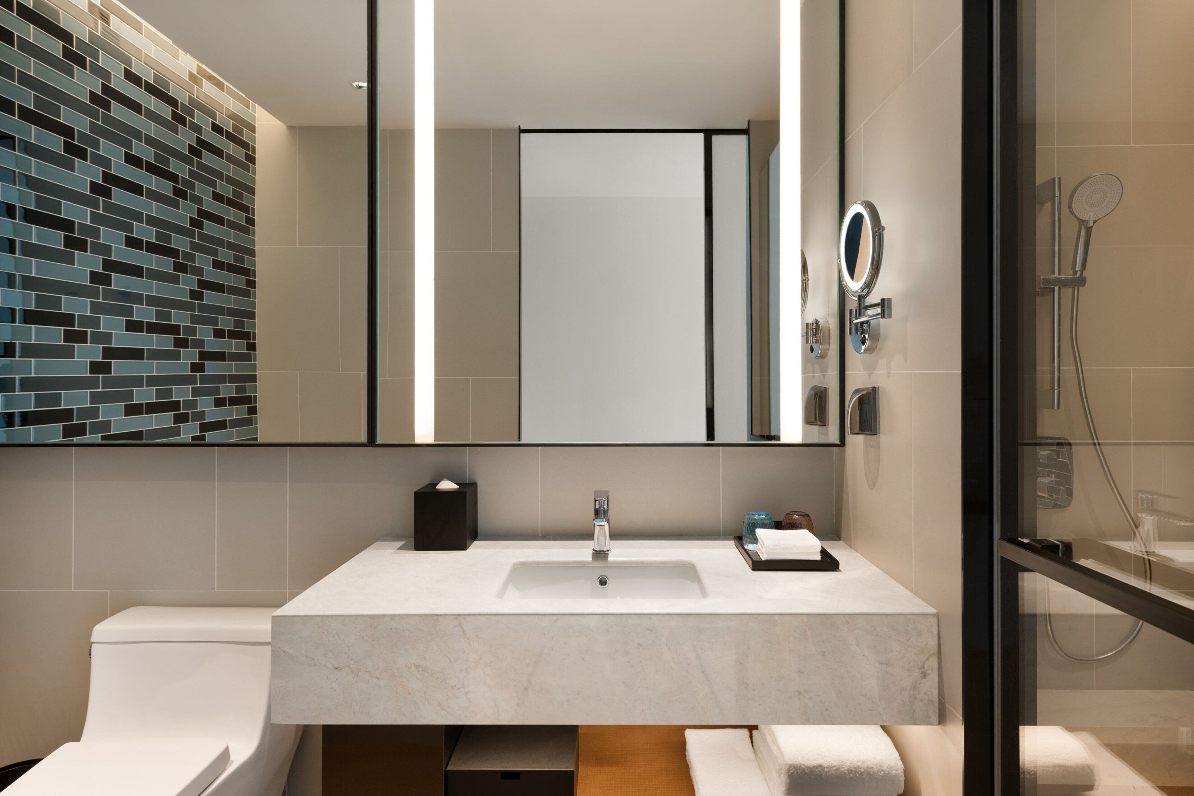 Une salle de bain moderne avec un grand miroir, un lavabo et un espace douche.