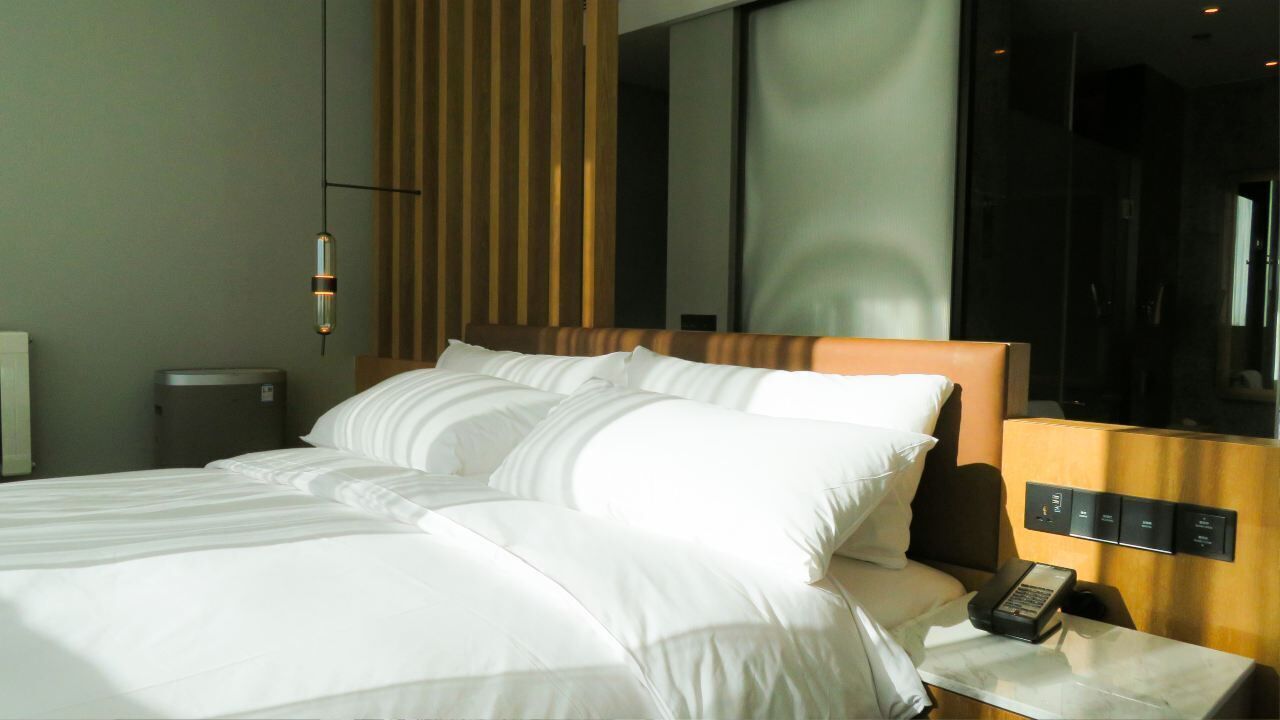 Una habitación de hotel con una cama grande, una mesita de noche con un teléfono y un espejo.