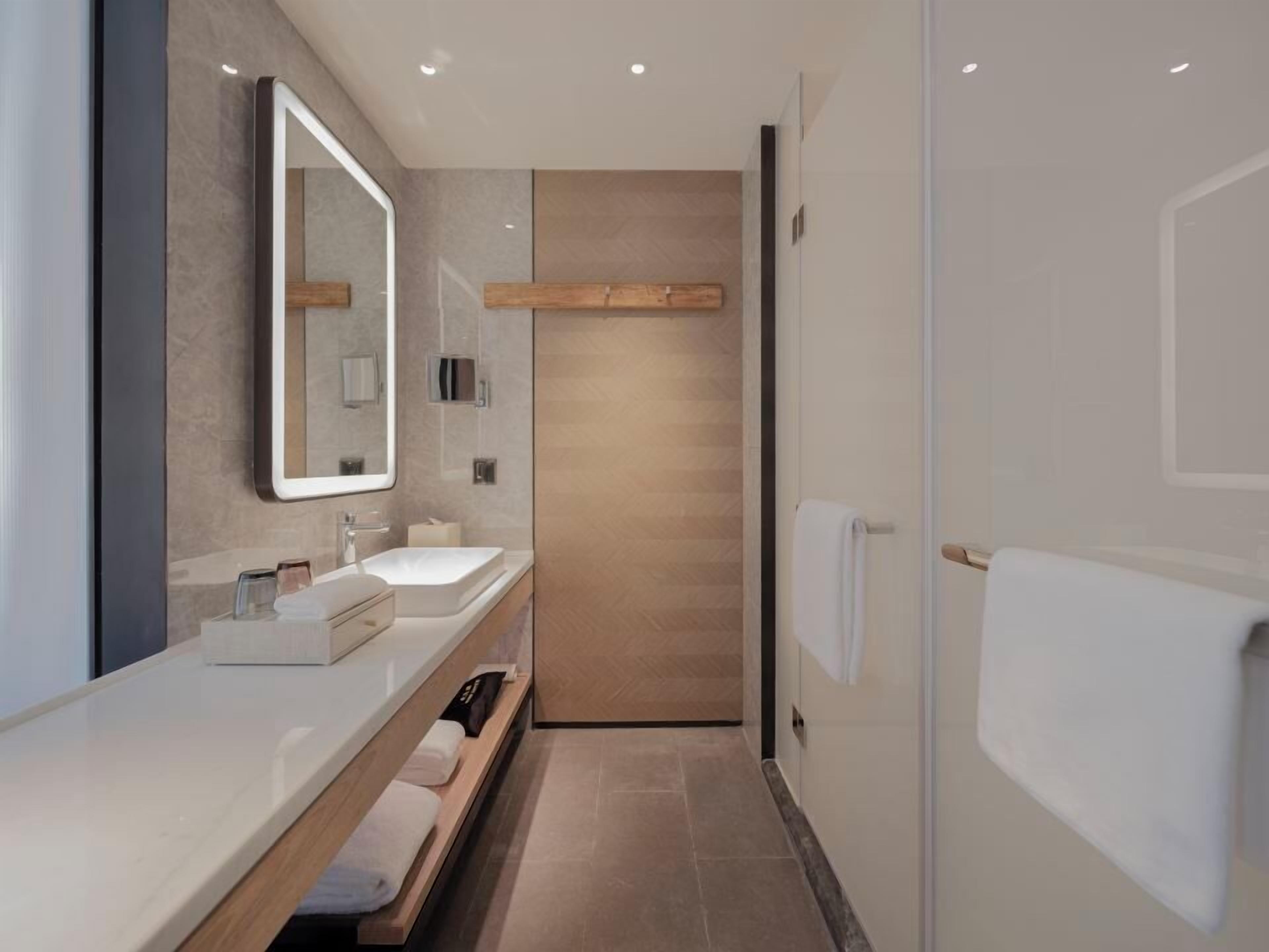 Une salle de bain moderne avec un grand miroir, deux lavabos, un porte-serviettes et un espace douche.