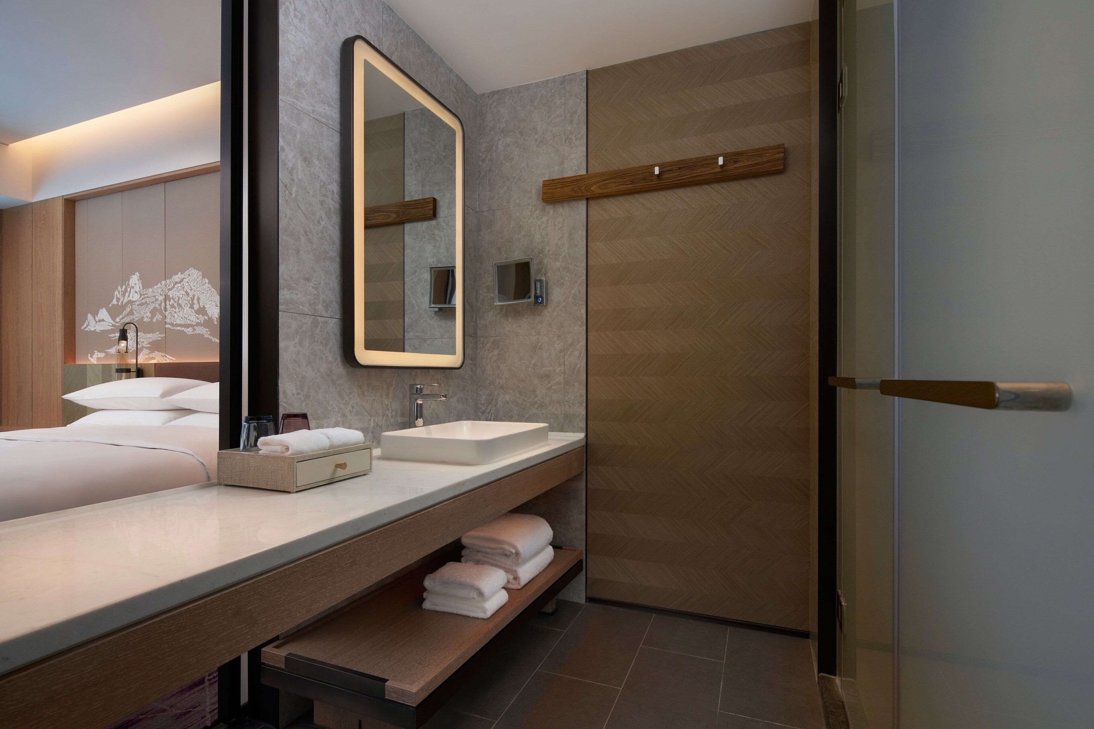 A modern bathroom with two sinks, a large mirror, and a shower area.